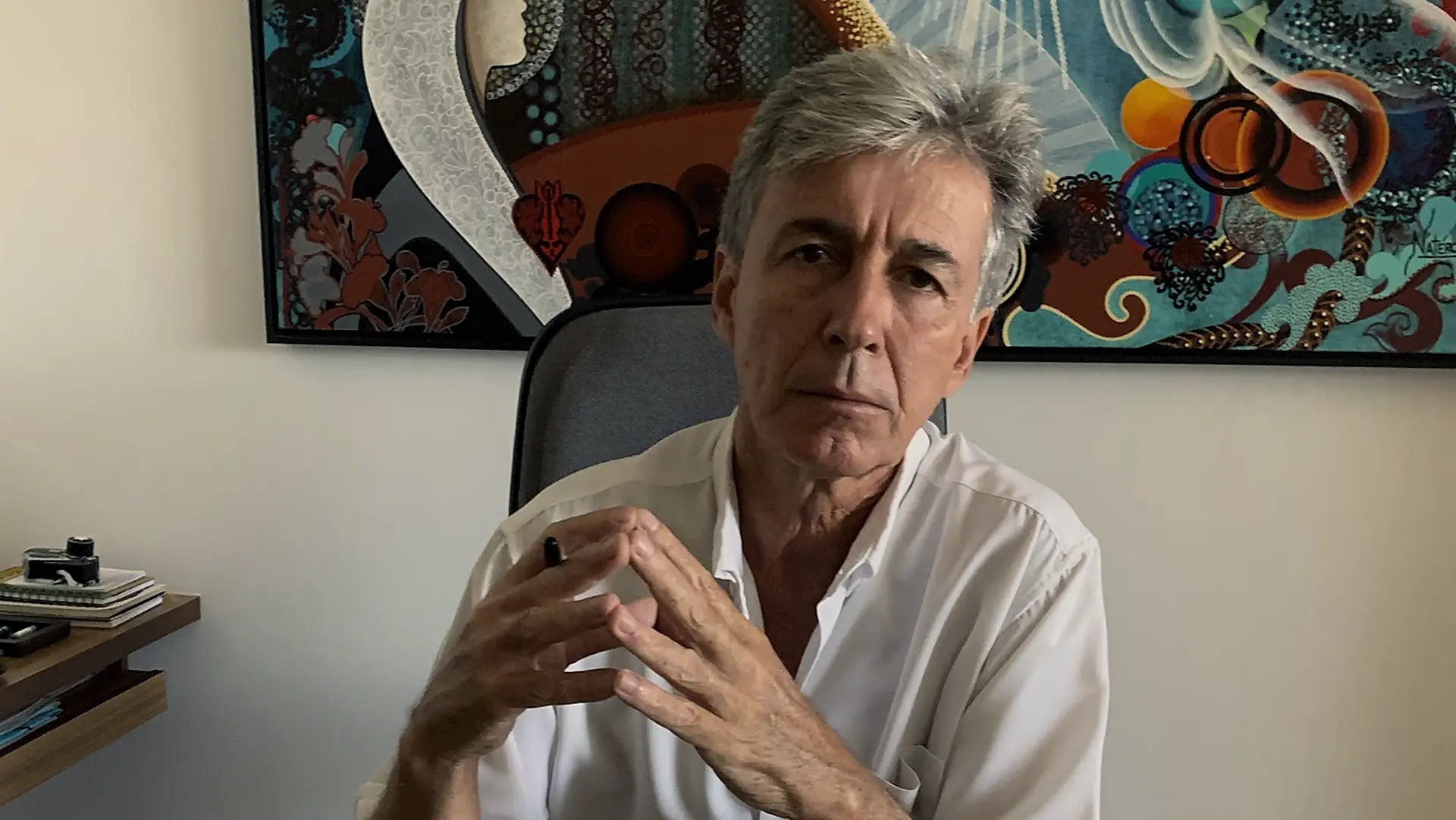 Luiz Fernando Magalhães em seu consultório, diante de um quadro azul e colorido